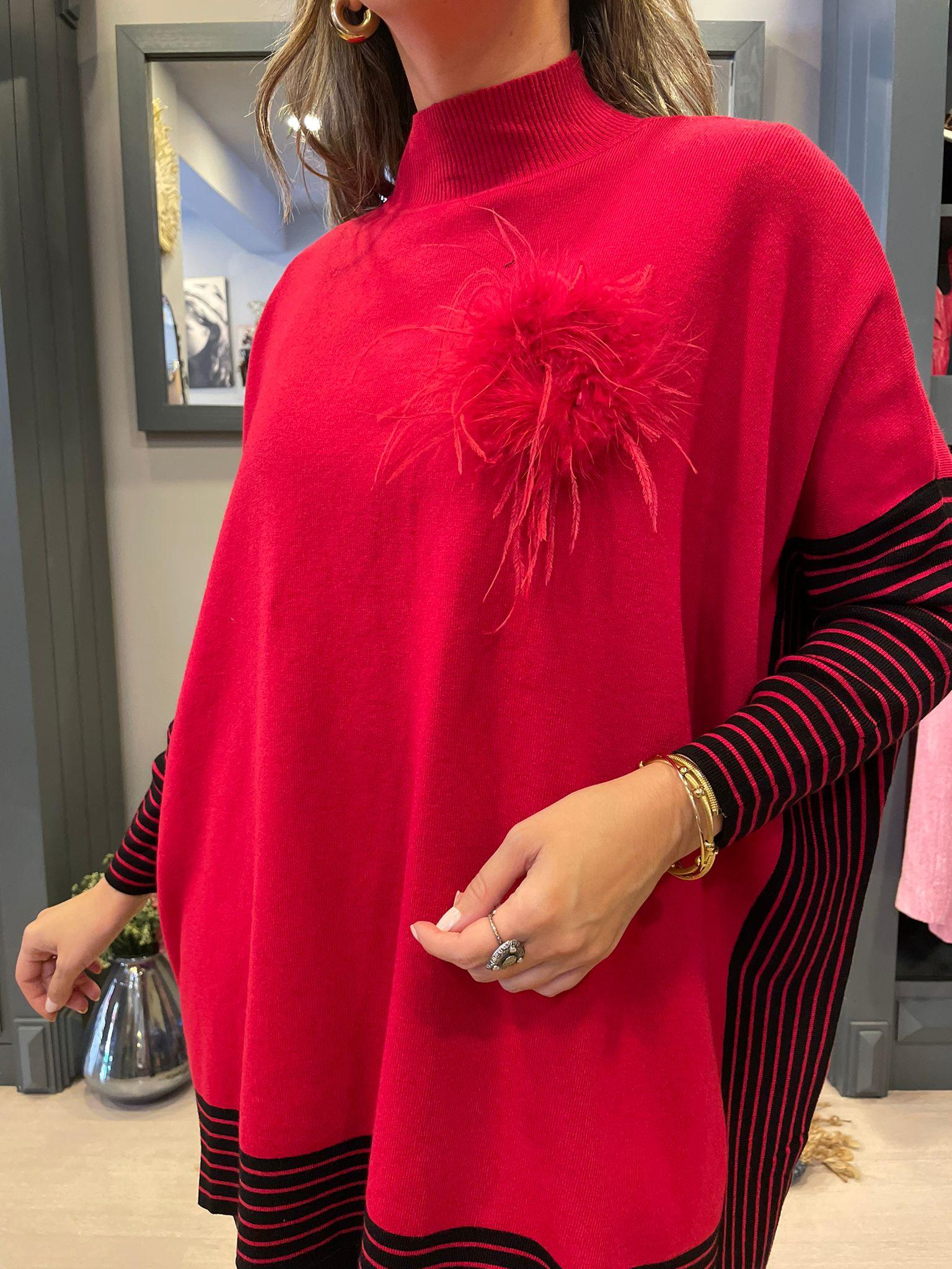 Jersey tipo poncho rojo con negro y broche de plumas.