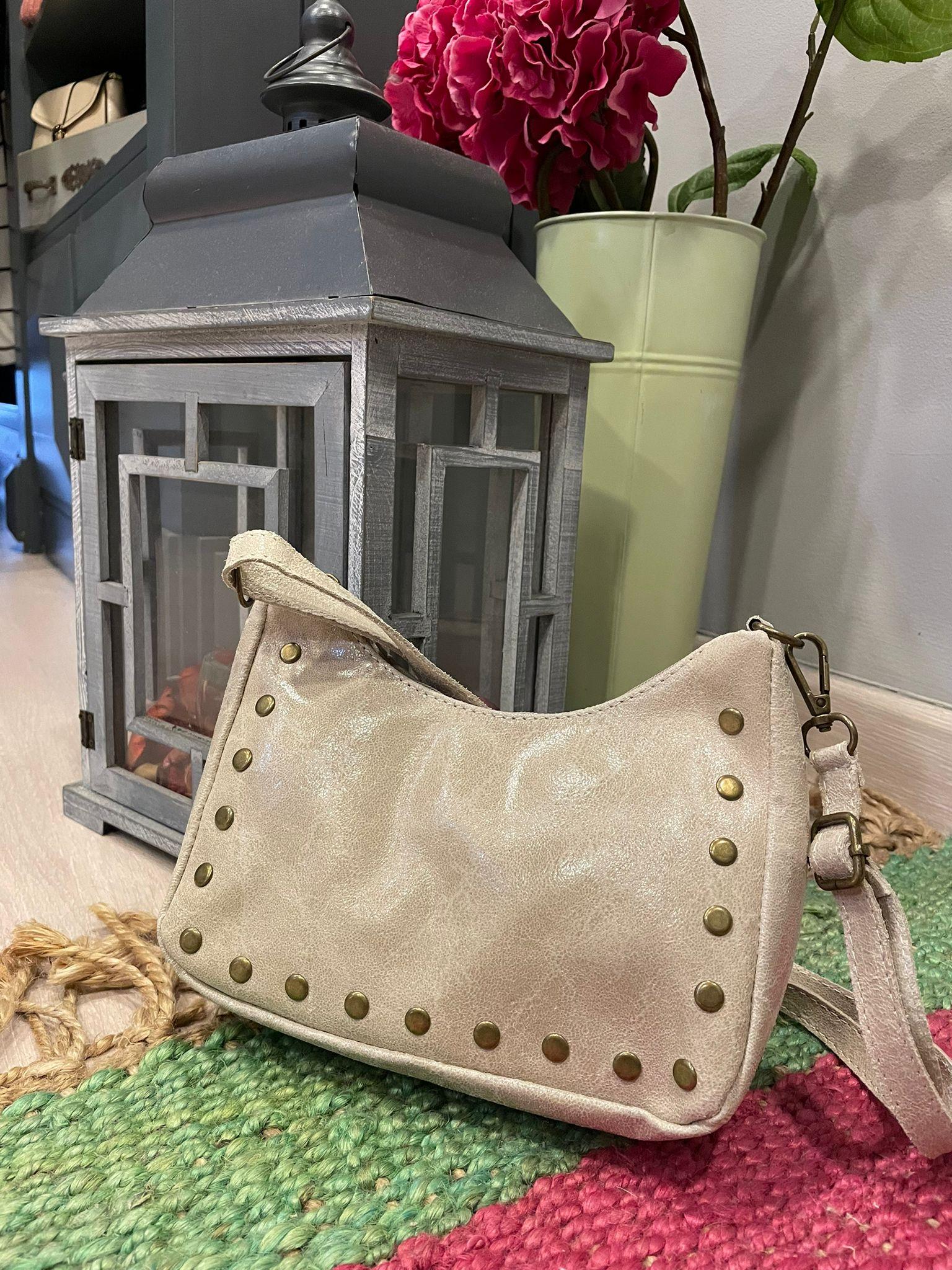 Bolso de piel con tachuelas y asa largo regulable.