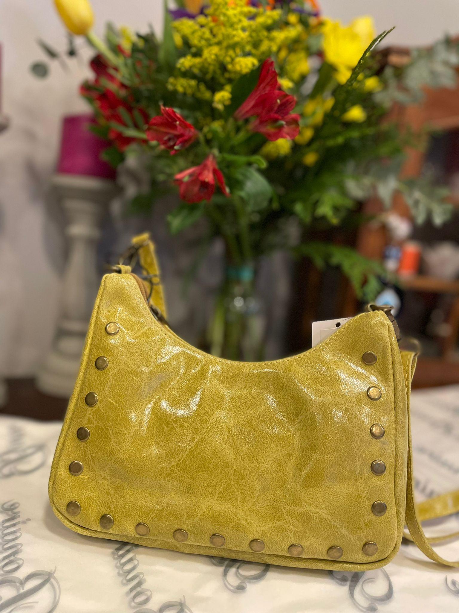 Bolso de piel con tachuelas y asa largo regulable.